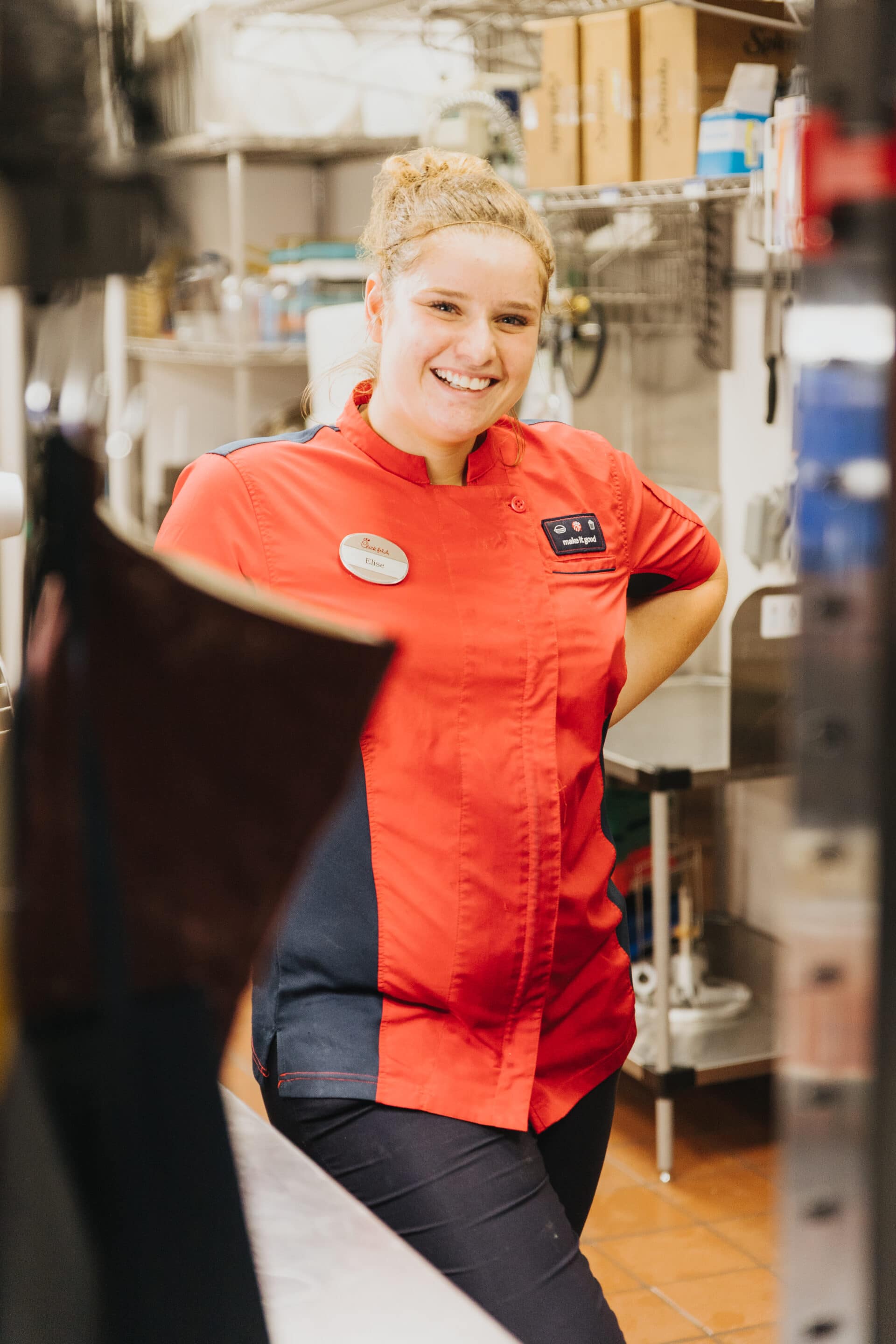 woman in restaurant kitchen waving 